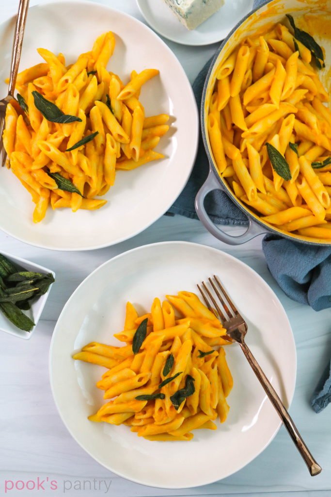Plates of pasta with squash sauce, garnished with fried sage leaves.