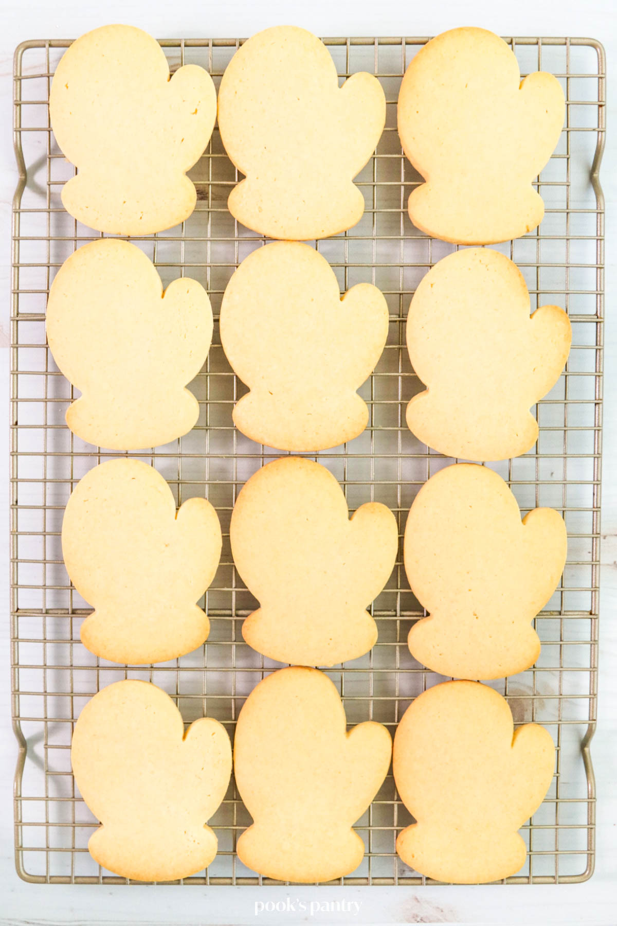 Mitten-shaped sugar cookies on a metal cooling rack.