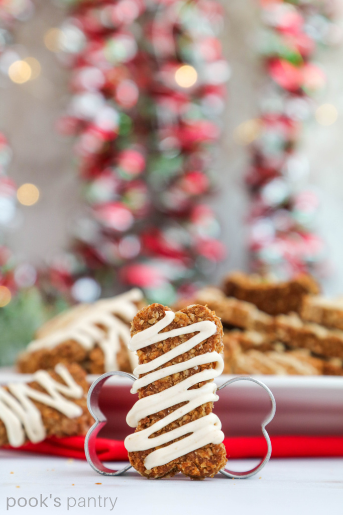 Christmas dog treats recipe with icing in front of cookie cutter.