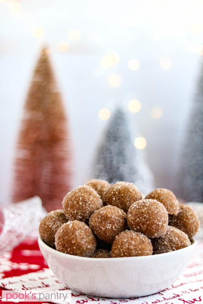 Whiskey balls coated in sugar in small bowl with Christmas lights.