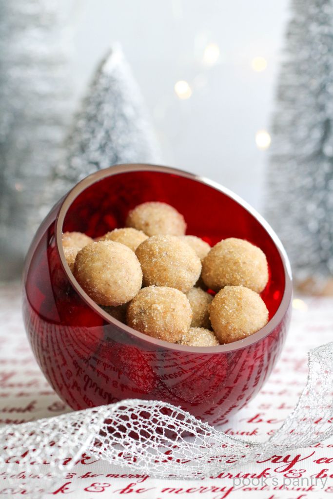 Maple rum balls in red glass bowl with silver ribbon in front.