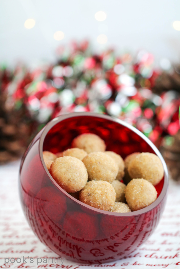 Maple rum balls in red bowl with white twinkle lights in the background.