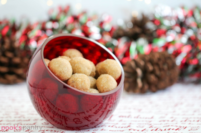 Rum balls on red and white tablecloth with pinecones in the background.