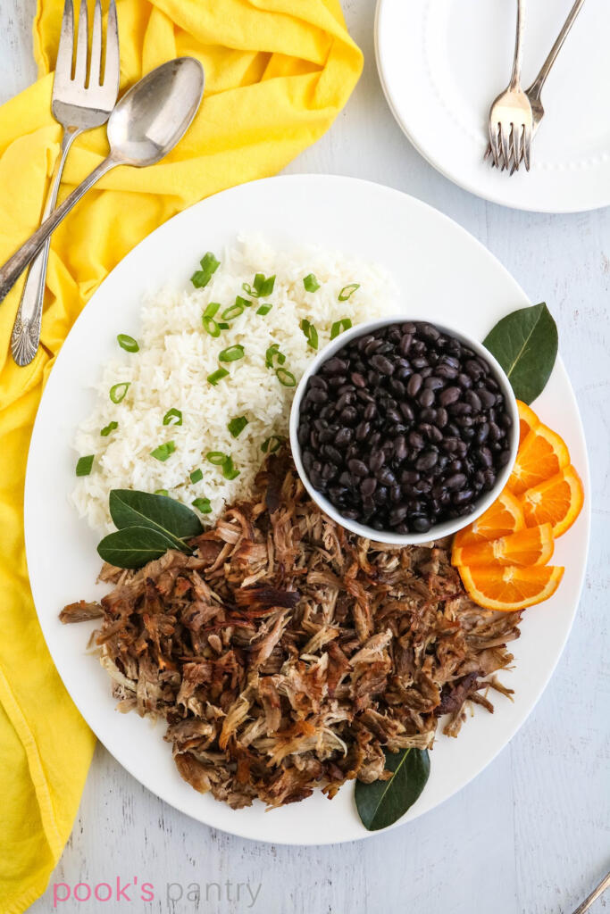 Cuban pulled pork with beans and rice on platter.