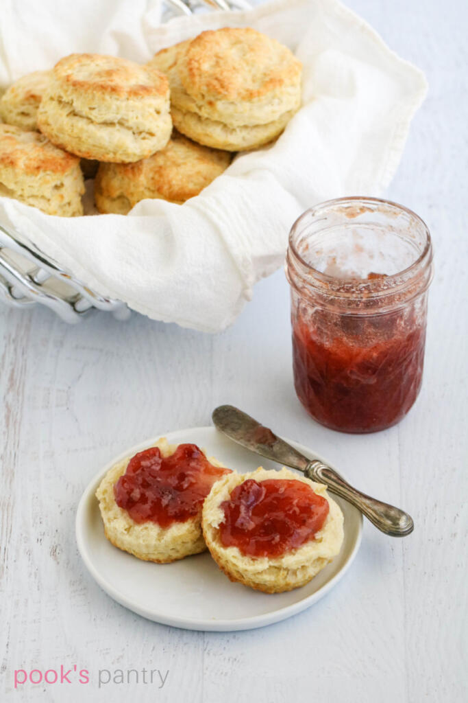 Buttermilk biscuit with strawberry jam on plate.