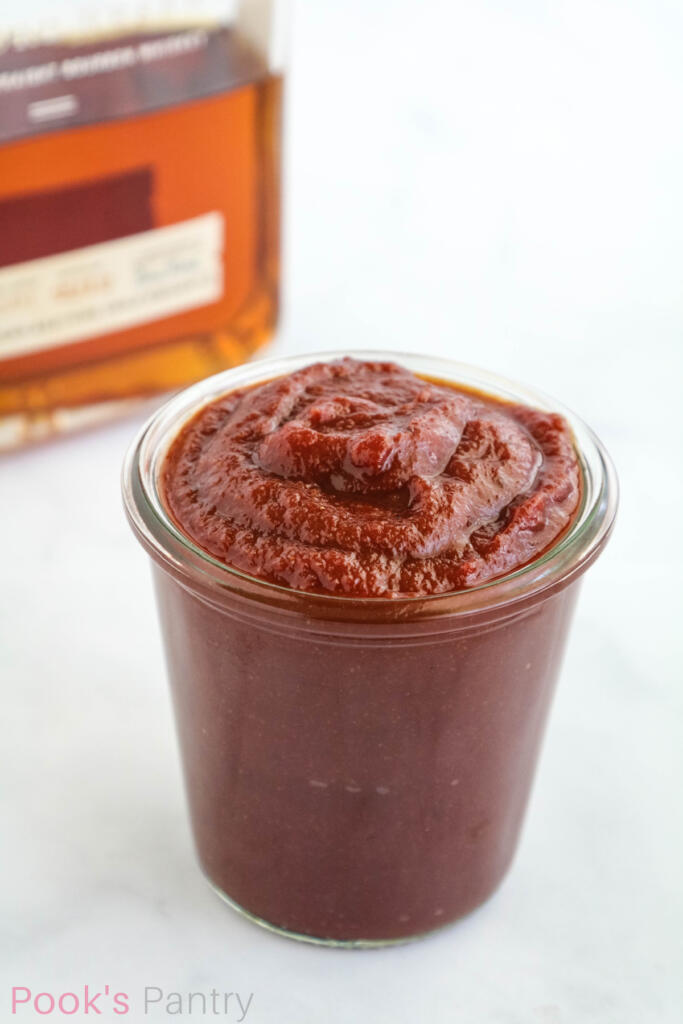 Homemade barbecue sauce with bourbon in glass jar.