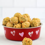 Meatballs for dogs in a red dish against a white background.