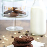 Triple chocolate cookies stacked on top of each other on a square of parchment paper.