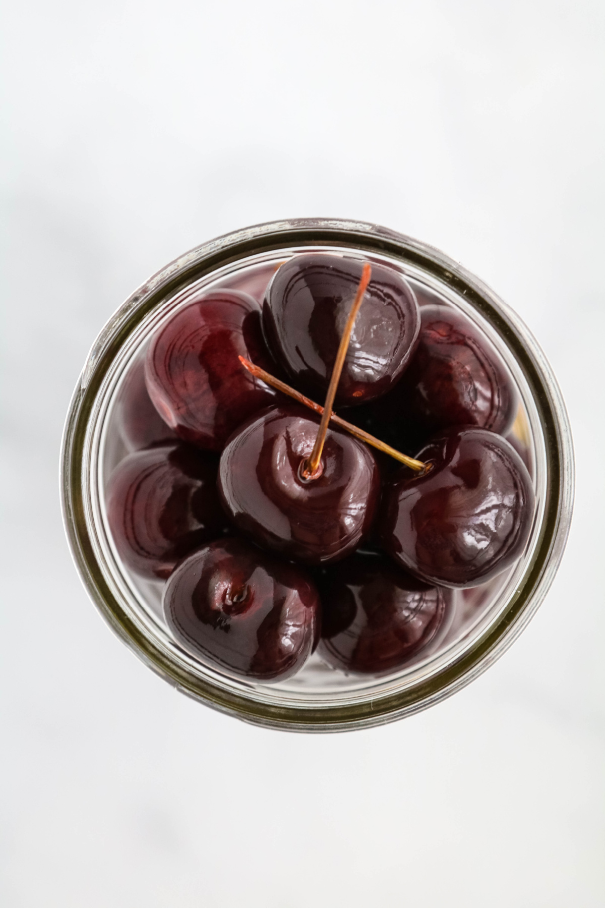 Pickled cherries in glass jar.