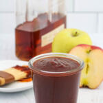 Apple bourbon BBQ sauce with apples and bourbon in the background.