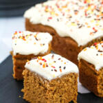 Square of pumpkin snack cake on a black wooden cutting board.