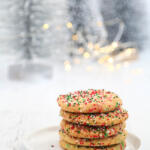 Christmas funfetti cookies stacked on a small white plate.