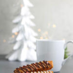 Peppermint biscotti with chocolate drizzle on a small white plate.