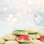 Sugar cookies for Christmas on a white platter with twinkly lights in the background.