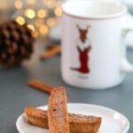 Brown sugar cinnamon biscotti on a small white plate with twinkly lights in the background.