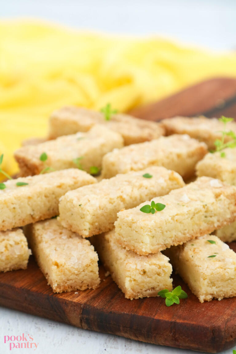 Lemon thyme shortbread cookies on wooden board with fresh herbs.