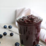 Blueberry bourbon BBQ sauce in a glass canning jar with blueberries scattered around it.