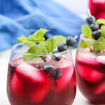 Blueberry lemonade in clear glasses, garnished with fresh blueberries and mint.