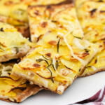 Slices of potato pizza on white platter.