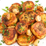 Melting potatoes with garlic and herbs on a white platter.
