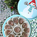 Gluten free rum balls in a round cookie tin with a snowman on top.