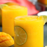 Frozen mango daiquiri in clear rocks glass with a slice of lime.
