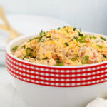 Pimento cheese potato salad in a white bowl with a red and white checkered rim.