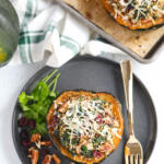 Vegetarian stuffed acorn squash on a black plate with pecans and cranberries on the side.