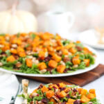 Roasted butternut squash salad on a white plate with a gold fork.