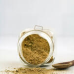 Homemade poultry seasoning in square glass jar, on a white background.