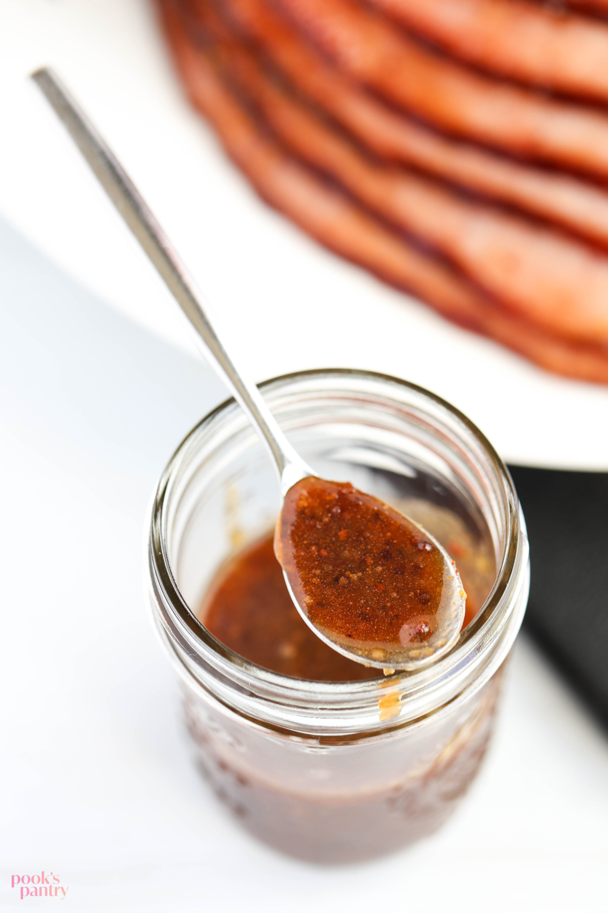 Glaze in a jar with a spoonful of glaze perched on top of the jar.