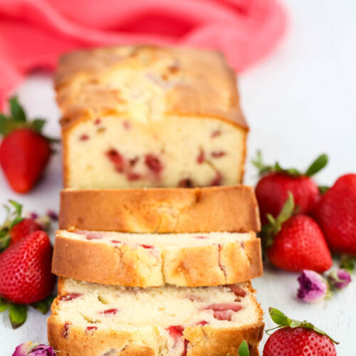 Strawberry cream cheese pound cake on a white background surrounded by fresh strawberries.