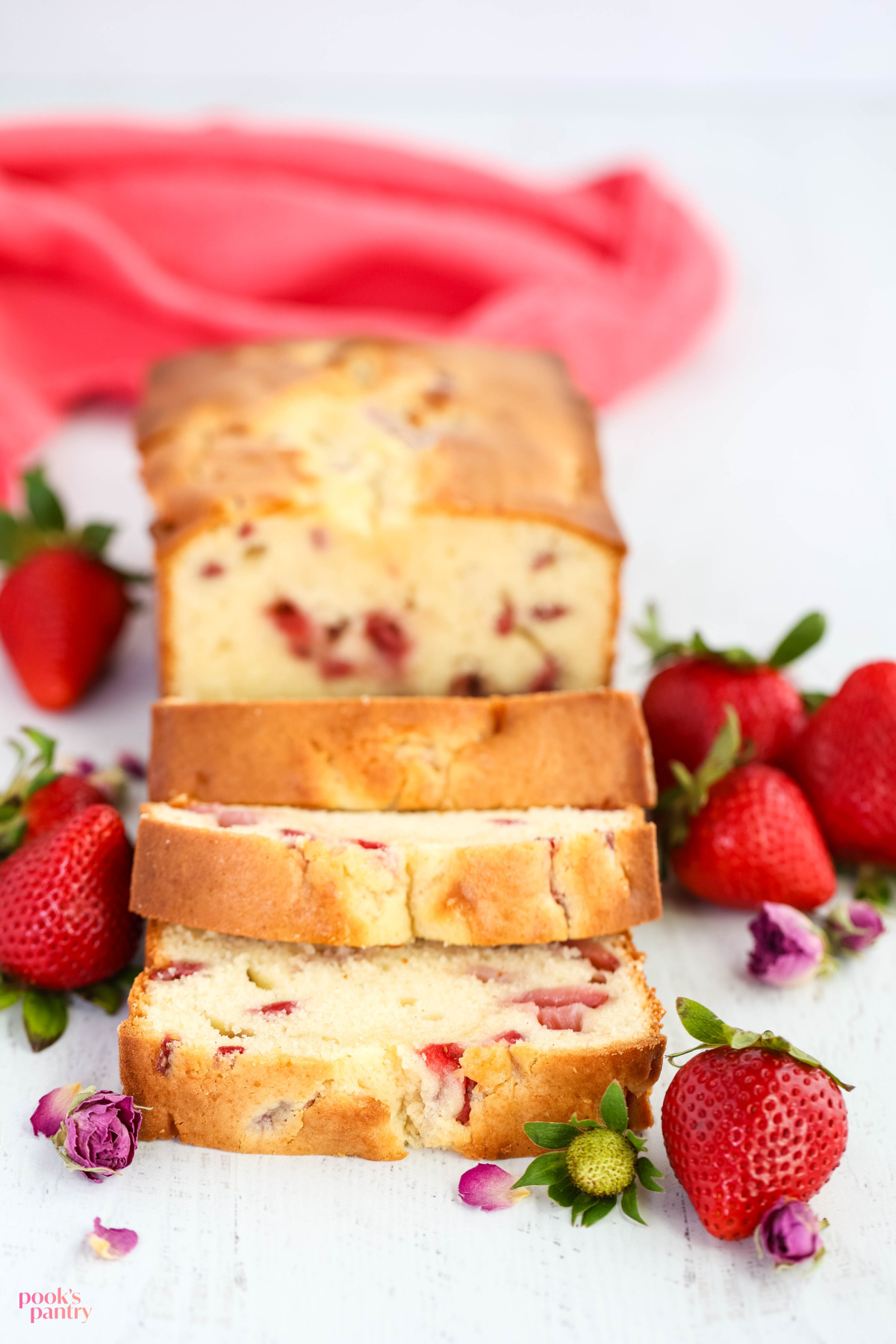 Strawberry cream cheese pound cake on a white background surrounded by fresh strawberries.