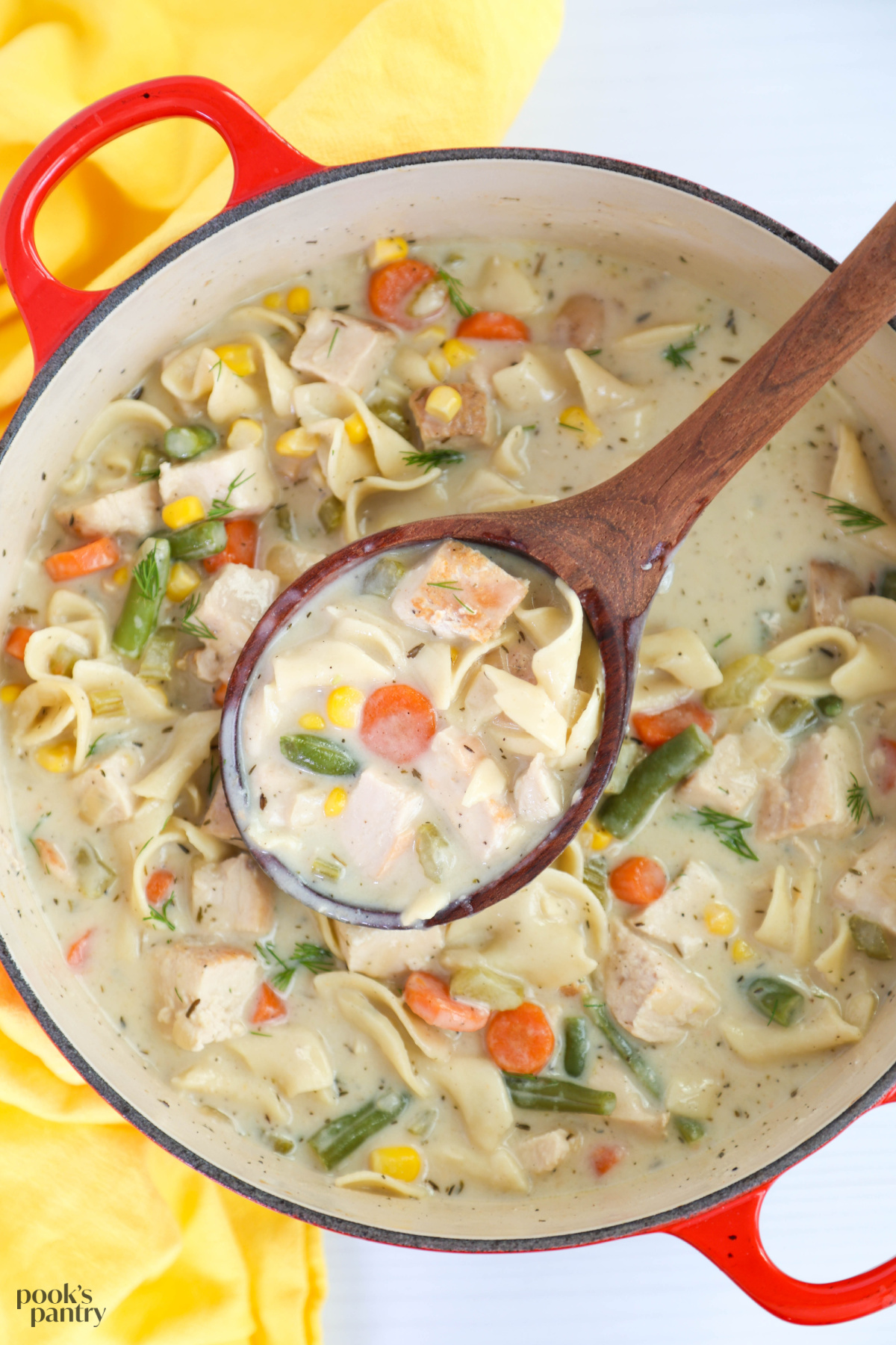 Creamy chicken noodle soup in a large red Dutch oven.