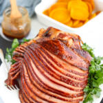 Honey mustard glazed ham recipe on a white platter with parsley on the side.