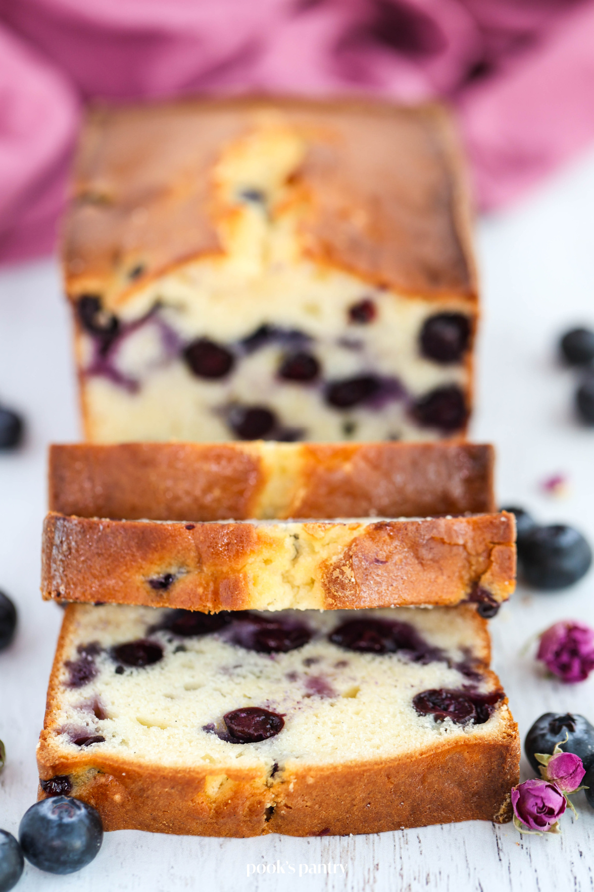 Sliced blueberry cream cheese pound cake on a white background.