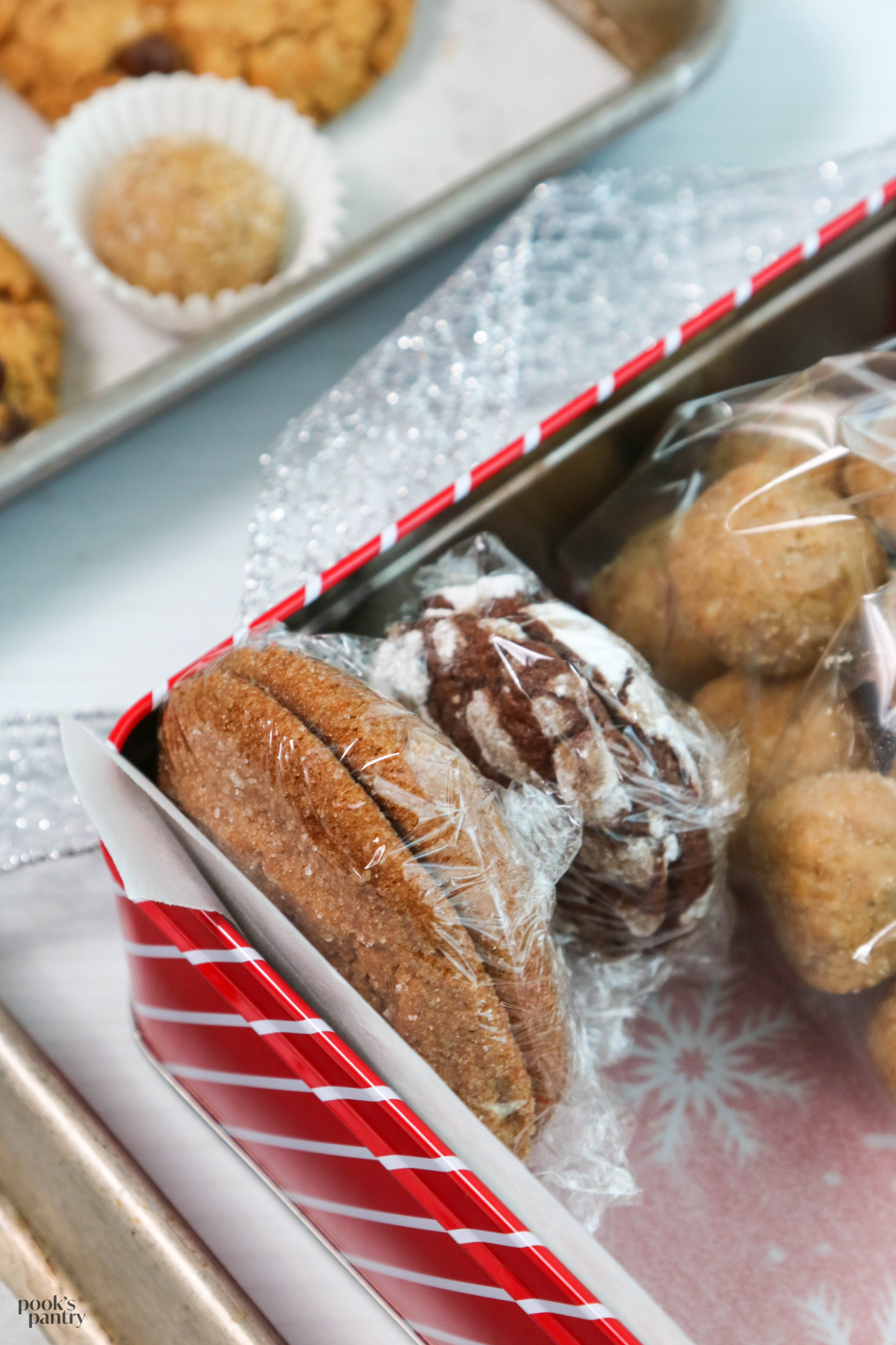Close up photo showing two cookies, bottom to bottom, wrapped tightly in plastic wrap inside of a cookie tin.