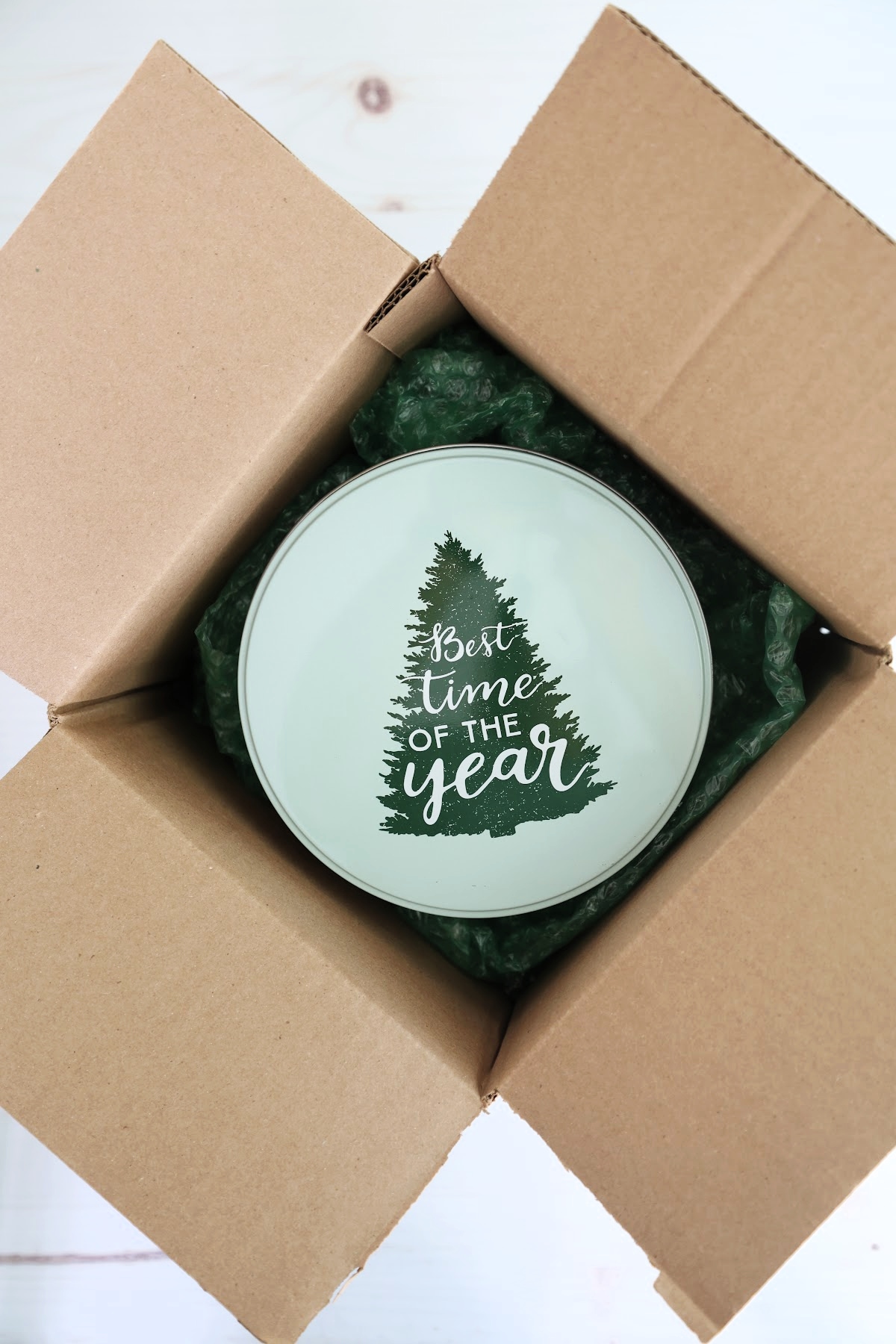 Packed cookie tin inside of a cardboard shipping box filled with bubble wrap for cushioning.