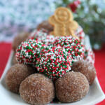 Gingerbread rum balls on a rectangular white plate. Half of the gingerbread balls are coated in red, white, and sprinkles. The other half are coated in sugar.