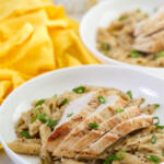 One pan chicken Dijon pasta garnished with scallions in a shallow, white bowl.