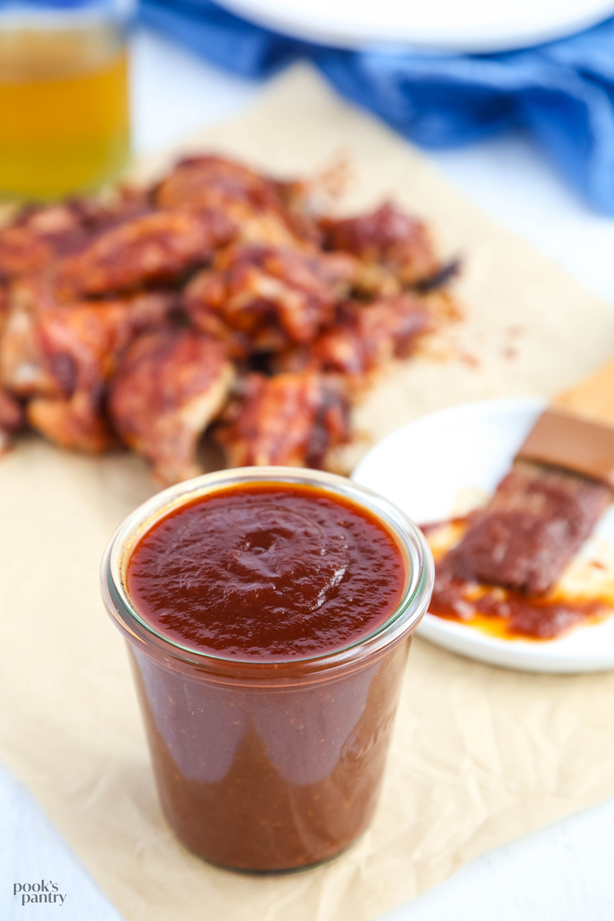 Maple barbecue sauce with bourbon, in a glass jar, with a pile of chicken wings in the background.
