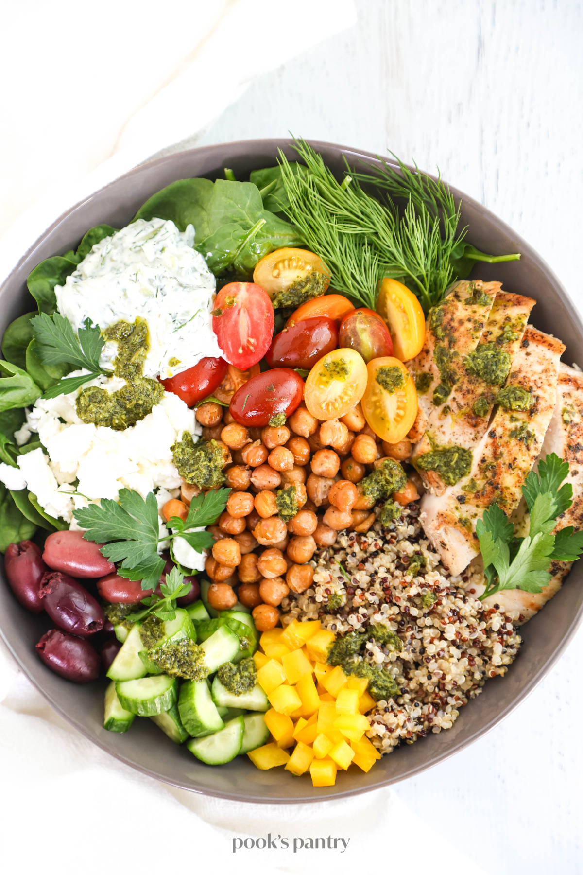 Mediterranean chicken salad in a gray bowl, with a white kitchen towel on the side.