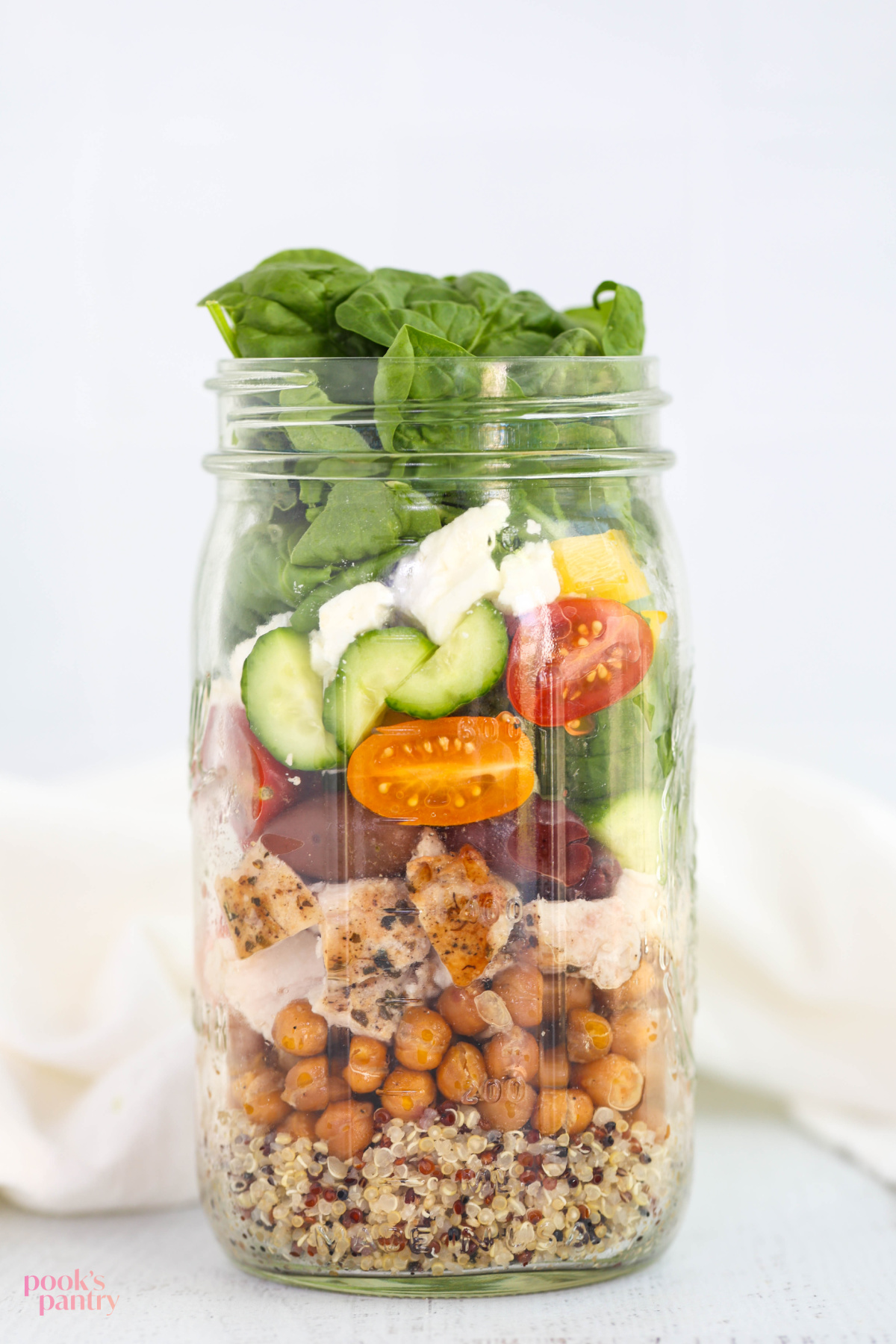Chicken meal prep salad layered in a glass jar, showing how to layer ingredients so they stay fresh.