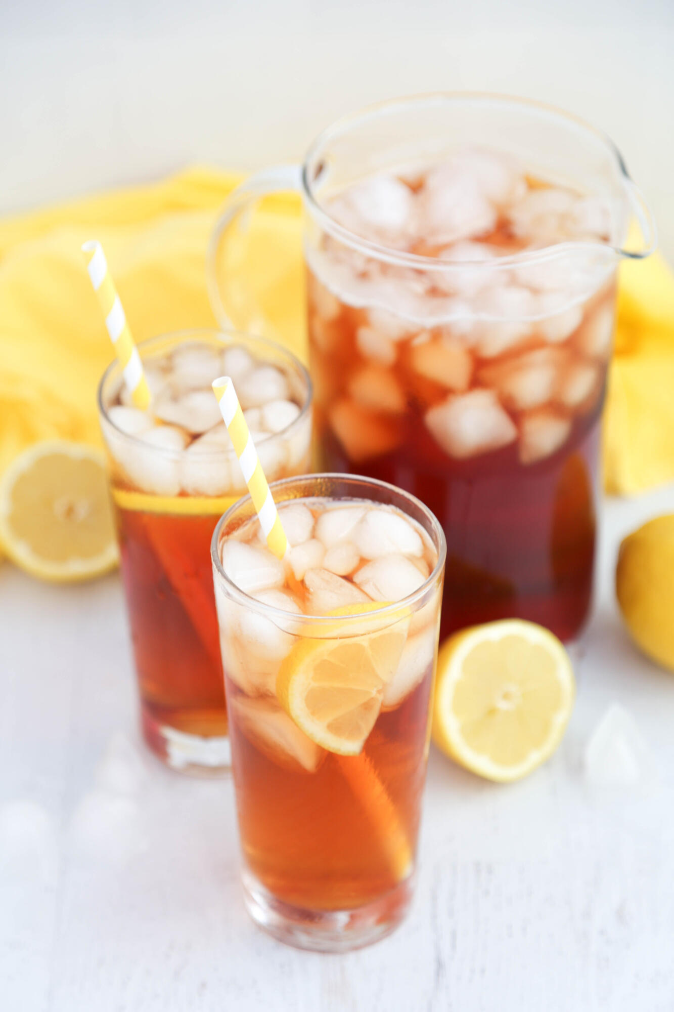 Glasses of Arnold Palmer, with a lemon wedge in the drink. The pitcher of tea is in the background.