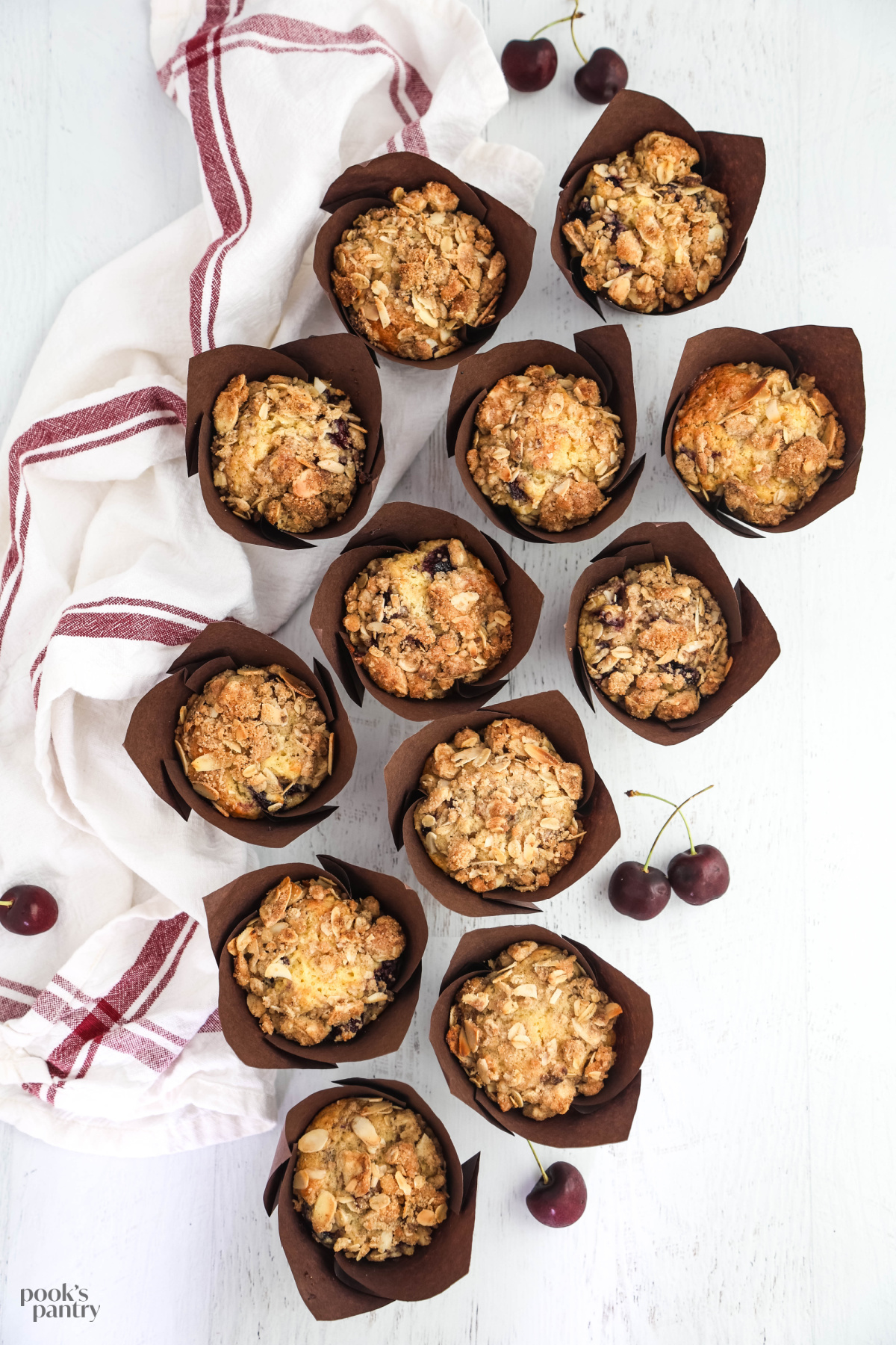 Muffins on a white background with a red and white kitchen towel on the side.