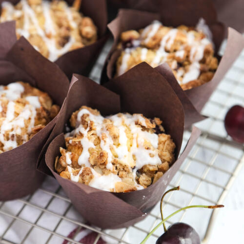 Fresh cherry muffin recipe in paper liners on a cooling rack.