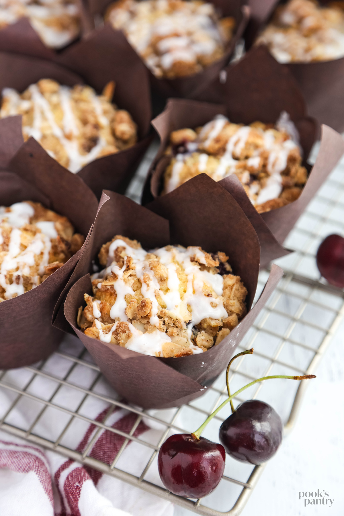 Fresh cherry muffin recipe in paper liners on a cooling rack.