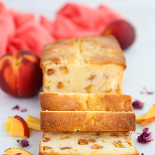 Peach pound cake slices, with slices of fresh peaches on the side of the cake.