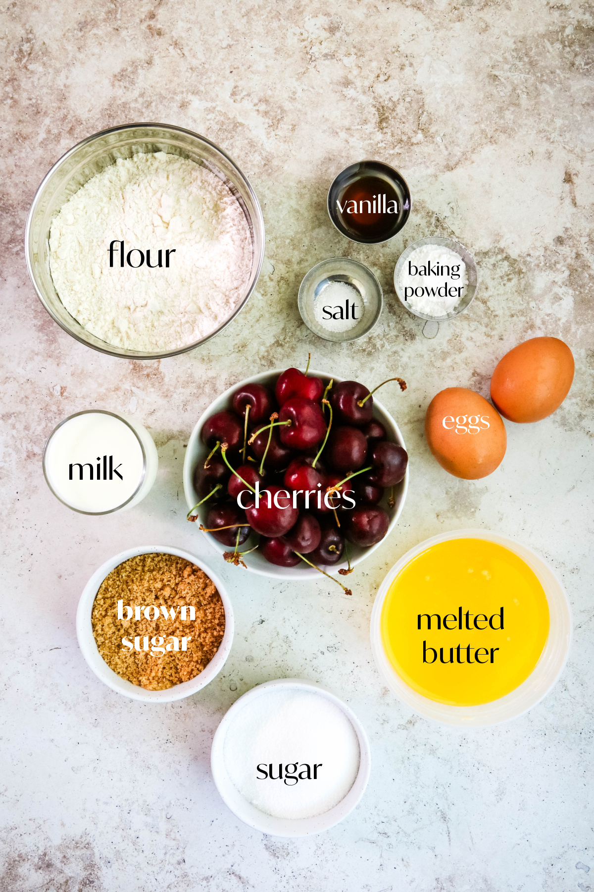 Ingredients for fresh cherries muffins on a tan background.