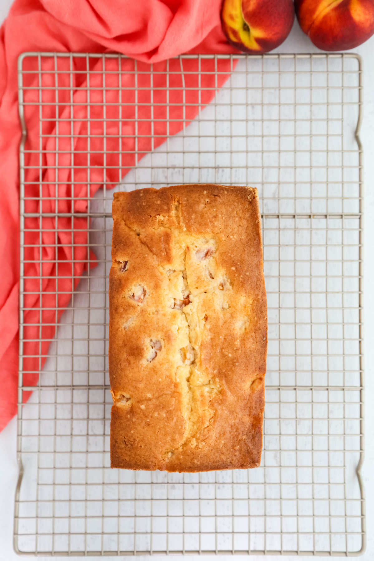 Peach loaf cake cooling on a metal rack.